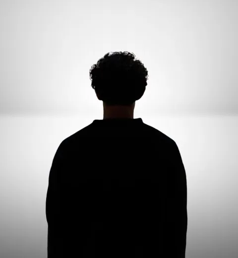 Marco L., de dos, en silhouette sur fond blanc